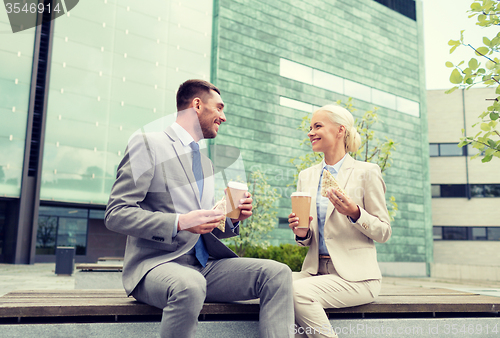 Image of smiling businessmen with paper cups outdoors