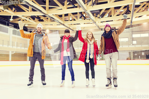 Image of happy friends waving hands on skating rink