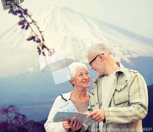 Image of happy senior couple with travel map over mountains