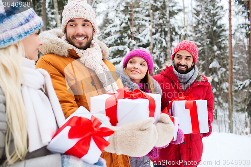 Image of happy friends with gift boxes in winter forest