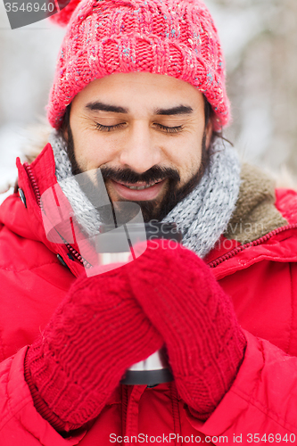 Image of happy man with thermos cup in winter forest