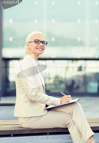 Image of young smiling businesswoman with notepad outdoors