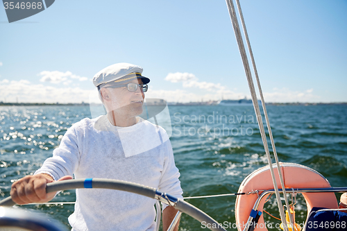 Image of senior man at helm on boat or yacht sailing in sea