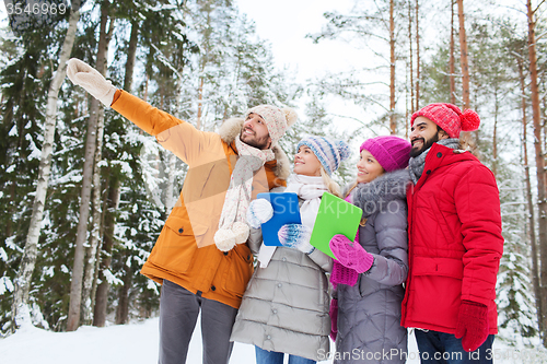 Image of smiling friends with tablet pc in winter forest