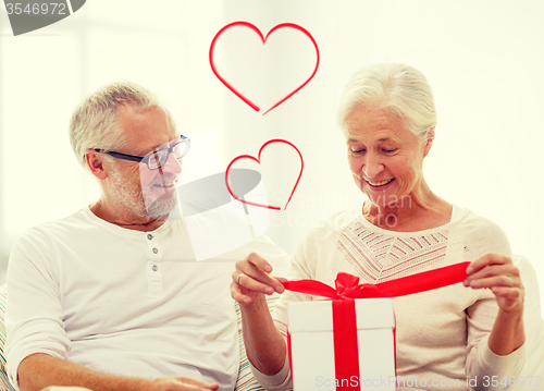 Image of happy senior couple with gift box at home