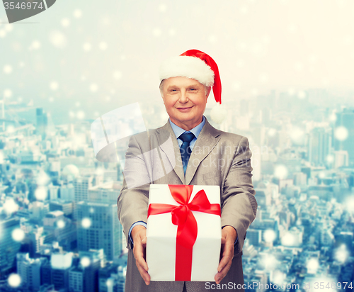 Image of smiling man in suit and santa helper hat with gift