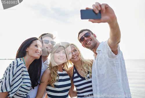 Image of happy friends on beach and taking selfie