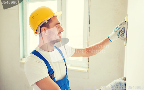 Image of smiling builder with grinding tool indoors