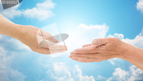 Image of close up of senior and young woman hands