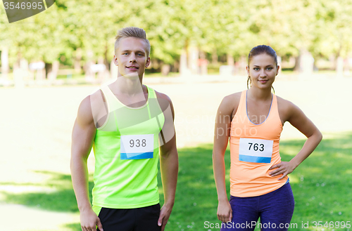 Image of happy friends or couple with racing badge numbers