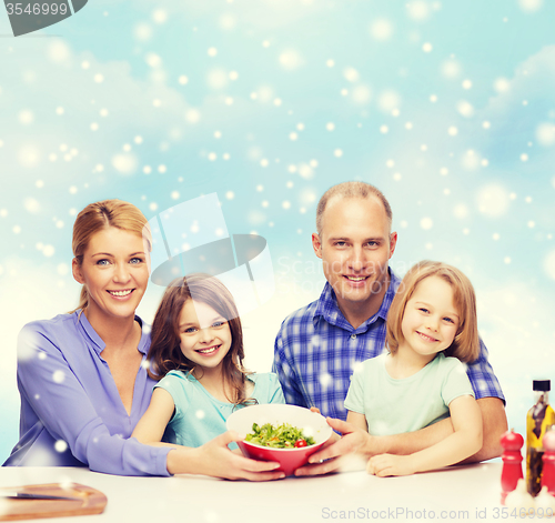 Image of happy family with two kids showing salad in bowl