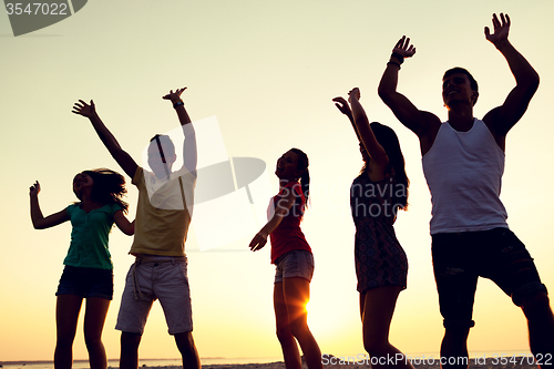 Image of smiling friends dancing on summer beach