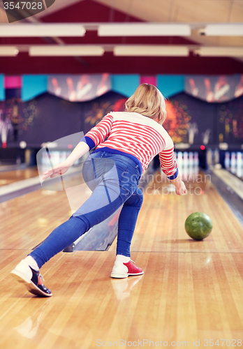 Image of happy young woman throwing ball in bowling club