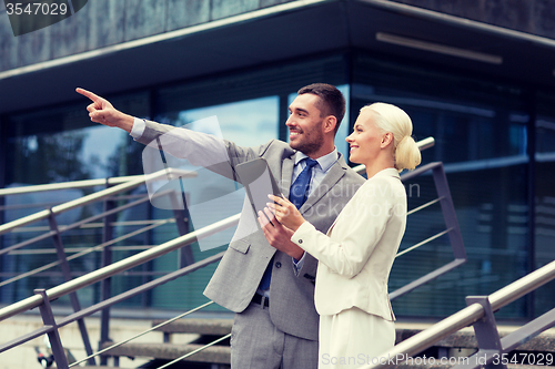 Image of smiling businessmen with tablet pc outdoors