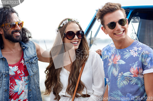 Image of smiling young hippie friends over minivan car