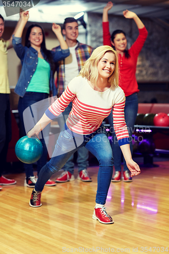 Image of happy young woman throwing ball in bowling club