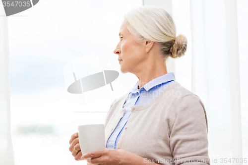 Image of lonely senior woman with cup of tea or coffee