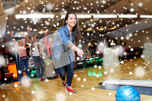 Image of happy young woman throwing ball in bowling club