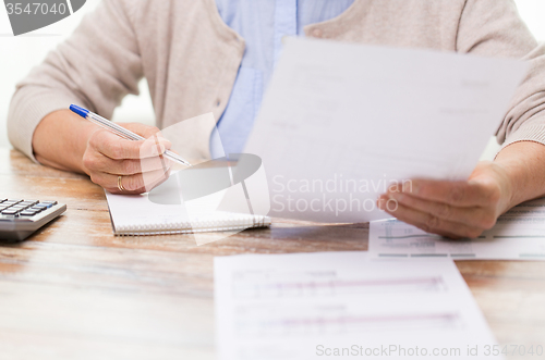 Image of senior woman with papers and calculator at home