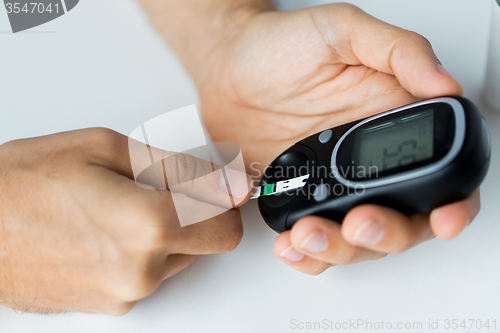 Image of close up of man checking blood sugar by glucometer