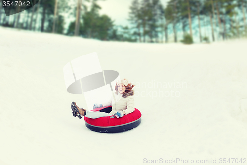 Image of happy teenage girl sliding down on snow tube