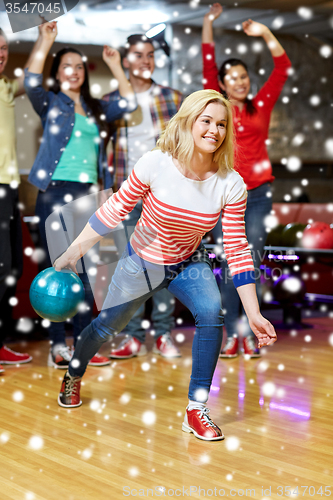 Image of happy young woman throwing ball in bowling club