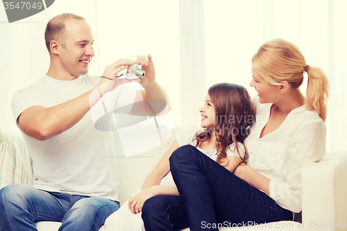 Image of happy father taking picture of mother and daughter