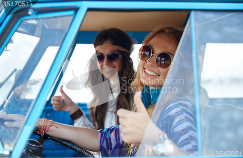 Image of smiling young hippie women driving minivan car