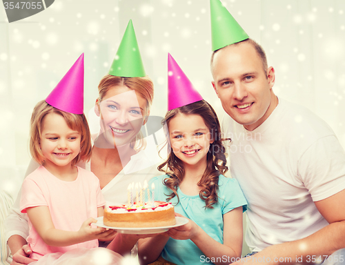 Image of happy family with two kids in party hats at home