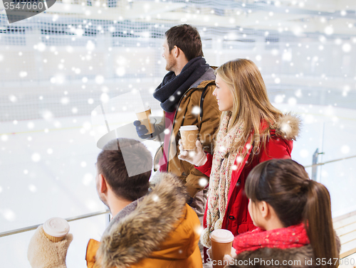 Image of happy friends with coffee cups on skating rink