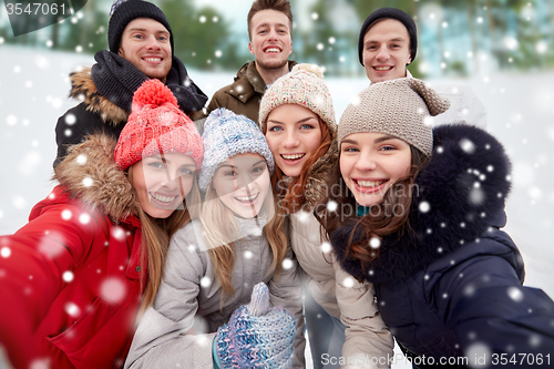 Image of group of smiling friends taking selfie outdoors