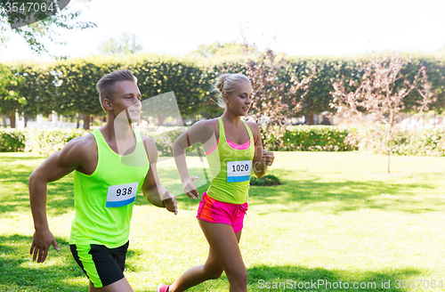 Image of happy sportsmen couple racing wit badge numbers