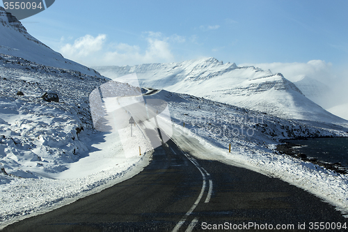 Image of Snowy and icy road with volcanic mountains in wintertime