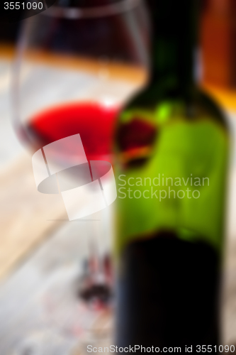 Image of red wine in glass and green bottle