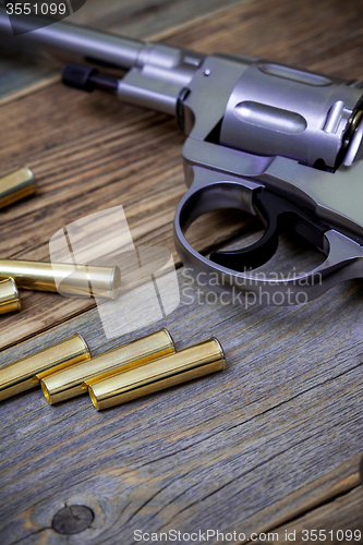 Image of Nagan revolver with cartridges on wood boards