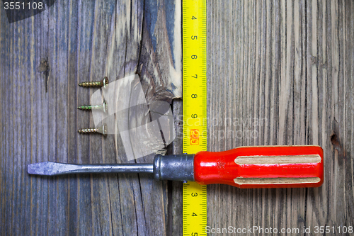 Image of old screwdriver, three screws and measuring tape 