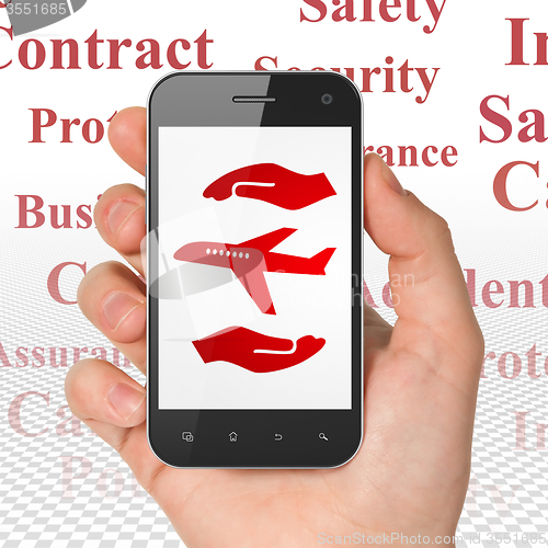Image of Insurance concept: Hand Holding Smartphone with Airplane And Palm on display