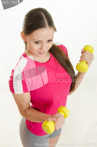 Image of The girl is engaged in fitness with two dumbbells