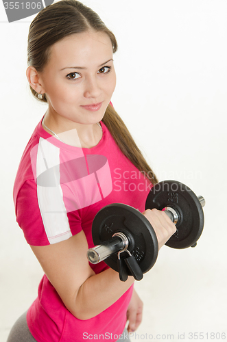 Image of Girl athlete looking up holding a dumbbell in her hand