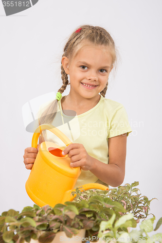 Image of Happy little girl watering flowers watering