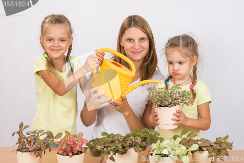 Image of Fun and funny mom and daughter watered flowers