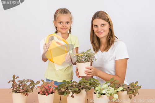 Image of Mom and daughter take care of potted flowers