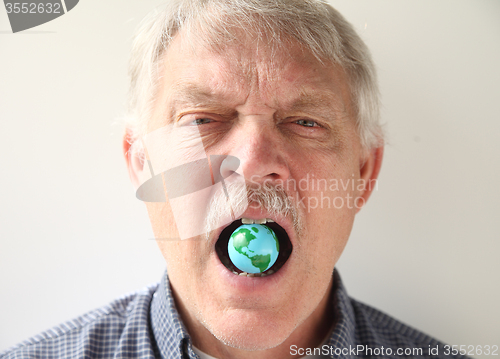 Image of man with earth model in his mouth 