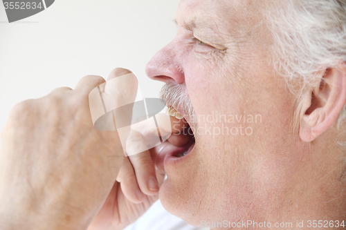 Image of older man flossing teeth profile view 