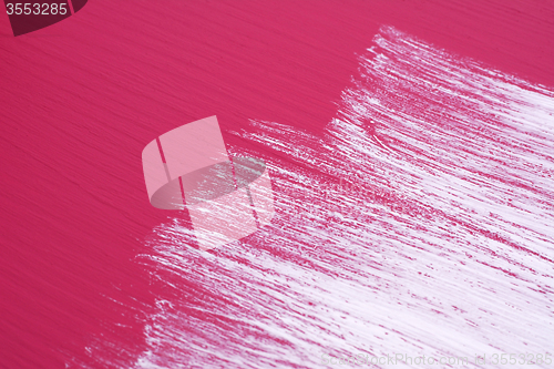 Image of Brush strokes of white paint across a pink surface