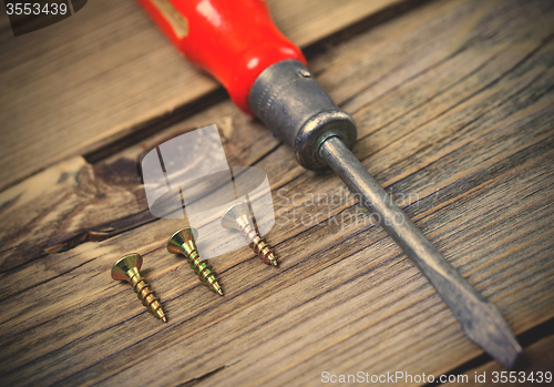 Image of screws and old screwdriver with a red wooden handle