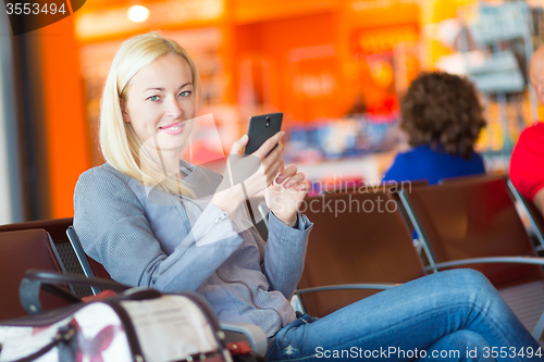 Image of Female traveler using cell phone while waiting.