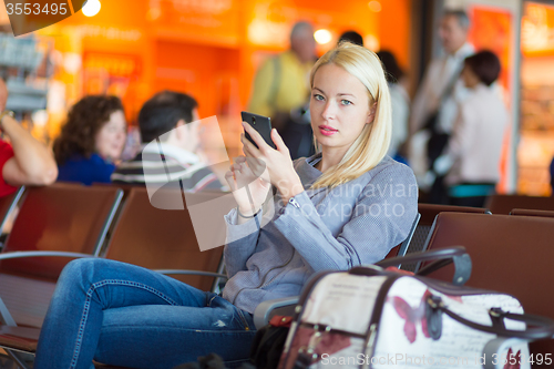 Image of Female traveler using cell phone while waiting.