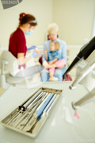 Image of Pediatric dentist explaining to young patient and her mother the model