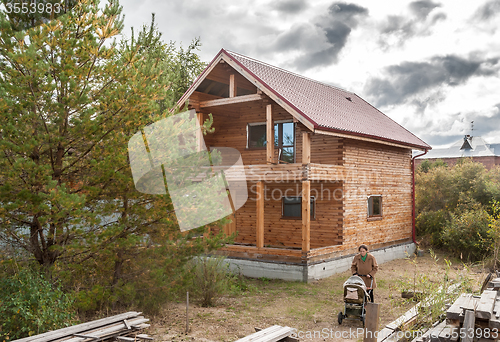 Image of Pretty mother with carriage near wooden house